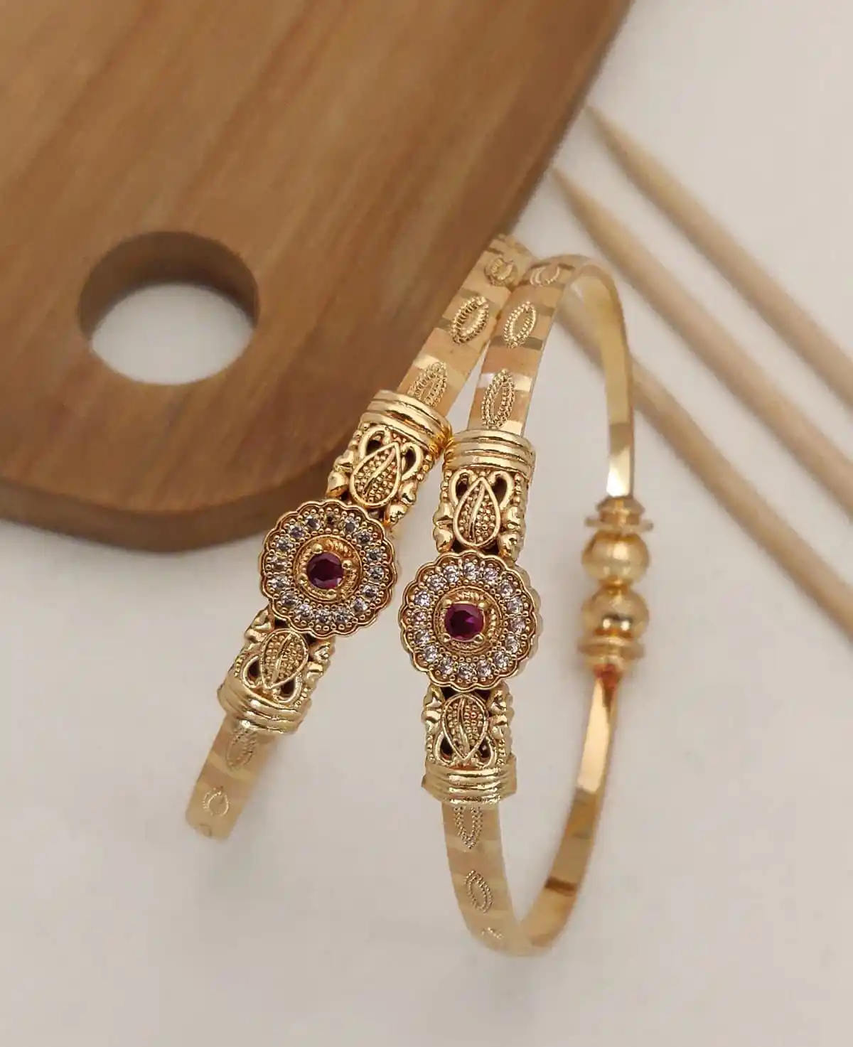 Delicate and elegant gold bangles with a floral design and a hint of pink.png